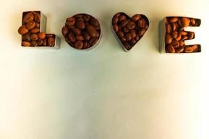 Beautiful texture with the word love for valentine's day inscription made from roasted selected brown natural aromatic Arabica coffee beans, robusta Copy space, flat lay, blue background photo