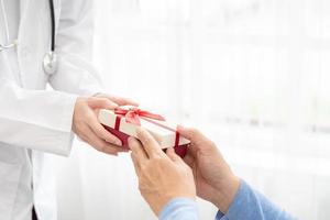 Doctor to senior old elderly people. Medical health care. senior's hand receives a gift box from doctor. photo