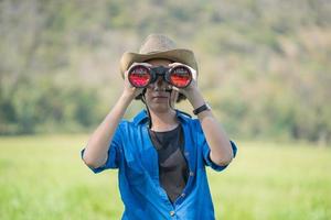 Woman wear hat and hold binocular in grass field photo