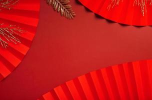 Paper fans and golden twigs on red background. Symbol Chinese new year top view with copy space photo