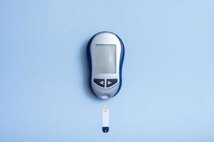 top vie medidor de glucosa sobre un fondo azul. concepto de prueba de diabetes foto