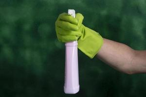 mano con guante protector que contiene envases de productos de limpieza utilizados para la higiene del hogar foto