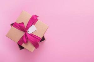 gift box with satin bow and tag on pink background with copy space photo