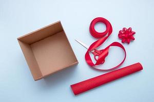 caja de regalo abierta, tijeras, cinta, papel de regalo, lazos para decorarlo