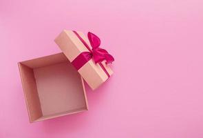 open empty gift box with satin ribbon bow on pink background photo