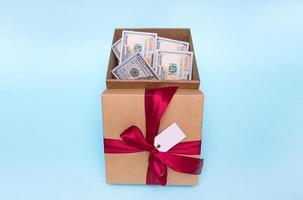 gift box filled with money, next to it is a lid tied with a satin ribbon and with an empty tag. photo