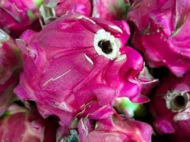 bunch of red sweet dragon fruit. several big sweet red dragon fruit put on wooden table on natural background for sale in fruit shop photo