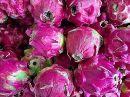 bunch of red sweet dragon fruit. several big sweet red dragon fruit put on wooden table on natural background for sale in fruit shop photo