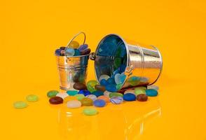 colored stones in glass in jar in bucket on orange background photo