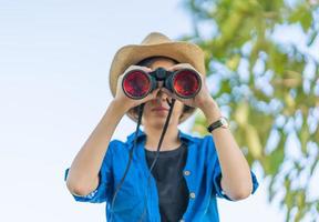 mujer de cerca use sombrero y sostenga binocular en el campo de hierba foto