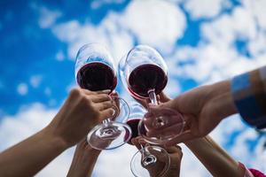 People clinking glasses with wine on the summer terrace of cafe or restaurant photo