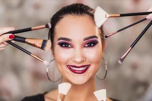 Cute Woman With Nice Makeup Surrounded By Make up Brushes photo