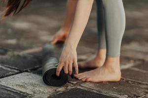 Woman Rolling Up Yoga Mat And Preparing To Outdoors Training photo