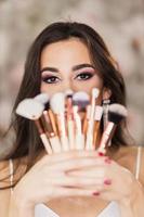 Portrait Of A Woman With A Nice Makeup Who Is Holding Makeup Brushes photo