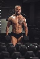 hombre entrenando con pesas para los músculos de sus brazos en el gimnasio foto