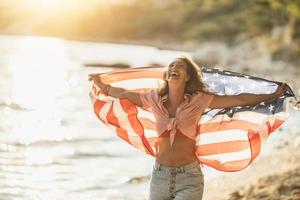 mujer con bandera nacional estadounidense disfrutando de un día en la playa foto