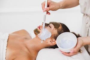 mujer recibiendo un tratamiento de máscara facial en el salón de belleza foto