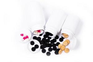 Medical pills spill out of a white jar on an isolated on white background photo