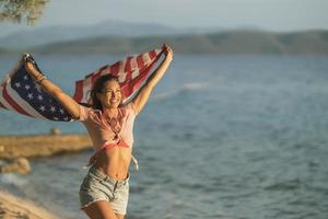 mujer con la bandera nacional estadounidense pasando el día en la playa foto