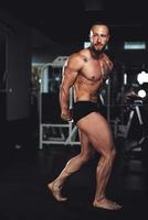 hombre fitness mostrando sus músculos en el gimnasio foto