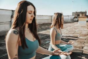 Two Woman Doing Yoga Outdoors On A Rooftop Terrace photo