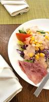 delicious breakfast, ham and fresh summer salad on white plate, on wooden table, view from above photo