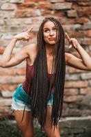 Woman With Long Afro Braided Hair Having Fun Against A Brick Wall photo