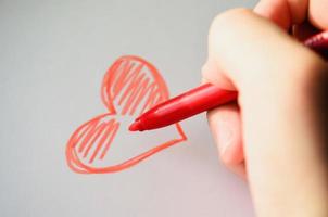 Draws a heart. Drawn heart. Love and Valentines day concept. Hand holds red felt-tip pen. Create your love. photo