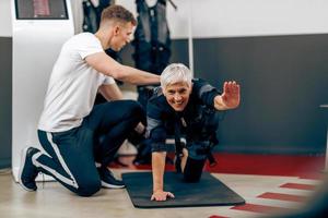 Senior Woman Doing EMS Workout With Coach In The Gym photo