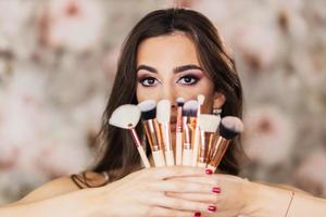 Portrait Of A Woman With A Nice Makeup Who Is Holding Makeup Brushes photo