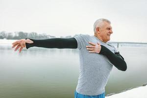 anciano estirando junto al río foto