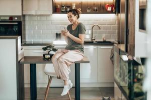 mujer usando un teléfono inteligente por la mañana en casa foto