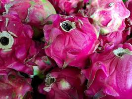 bunch of red sweet dragon fruit. several big sweet red dragon fruit put on wooden table on natural background for sale in fruit shop photo