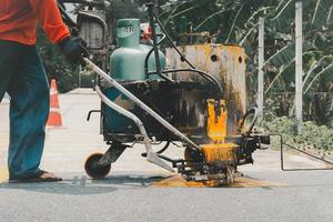 Road worker paint traffic lines on asphalt road surface. photo