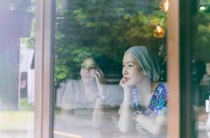 Two woman have coffee together in cafe, view through window glass. photo