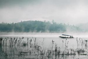 A man rowing his boat in Sangkhlaburi, thailand photo