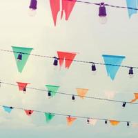 Colorful bunting flags and light bulbs on sky with retro filter effect photo
