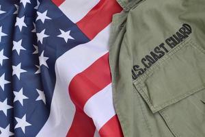 El viejo uniforme de la guardia costera de EE. UU. se encuentra en la bandera de los Estados Unidos doblada foto