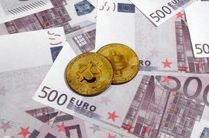 bitcoins sobre pila de billetes de quinientos euros. dinero tradicional versus concepto de criptomoneda. moneda de oro por encima de los billetes de 500 euros. de cerca foto