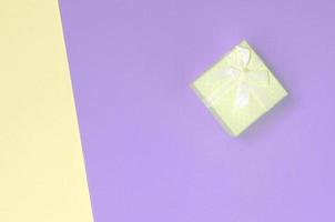 Small yellow gift box lie on texture background of fashion pastel yellow and violet colors photo