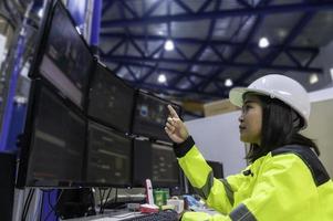 Inside the large Industry Factory Female Computer Engineer Works on Personal Computer She coding program for control machine,Thailand people work on fours monitors,Programmer working with serious photo