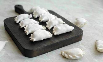 hermosas albóndigas rellenas crudas en una tabla de cortar de madera foto