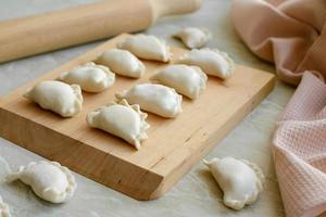 Beautiful raw stuffed dumplings on a wooden cutting board photo