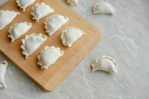 Beautiful raw stuffed dumplings on a wooden cutting board photo