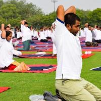 New Delhi, India, June 21 2022 - Group Yoga exercise session for people at Yamuna Sports Complex in Delhi on International Yoga Day, Big group of adults attending yoga class in cricket stadium photo