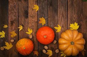 Thanksgiving background. Pumpkins and fallen leaves on white wooden background.  Halloween or Thanksgiving day or seasonal autumnal.  Flat lay. Top view photo
