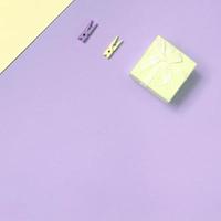 Small yellow gift box and two pegs lie on texture background of fashion pastel yellow and violet colors paper photo