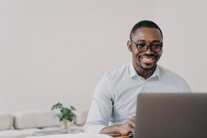 Smiling african american man software developer working online at laptop reads email with good news photo
