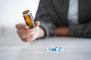 Close up female patient holding jar with medicine pills, vitamins, medication capsules for cure photo