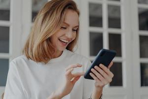 Happy young woman using mobile apps, holding modern smartphone, shopping online. E-commerce concept photo